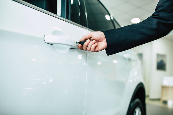 Close up of male hand opening car door with key help at dealership - 写真・画像