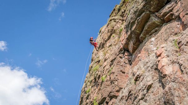 Αναρρίχηση βράχου. Ένας νεαρός ορειβάτης ανεβαίνει ένα κάθετο γρανιτένιο βράχο. Ακραίο άθλημα - Φωτογραφία, εικόνα