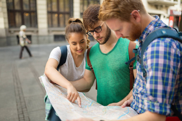 Young happy tourists holding map sightseeing in city - Photo, Image