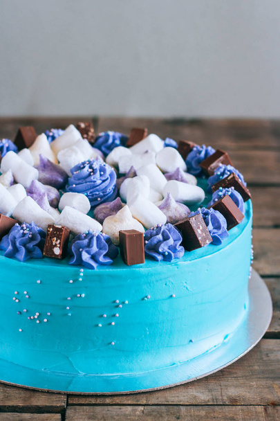 Blue festive cake with merengue and chocolate cubes on a wooden background - Photo, Image