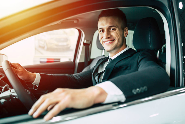 Happy businessman in suit driving car - Foto, afbeelding