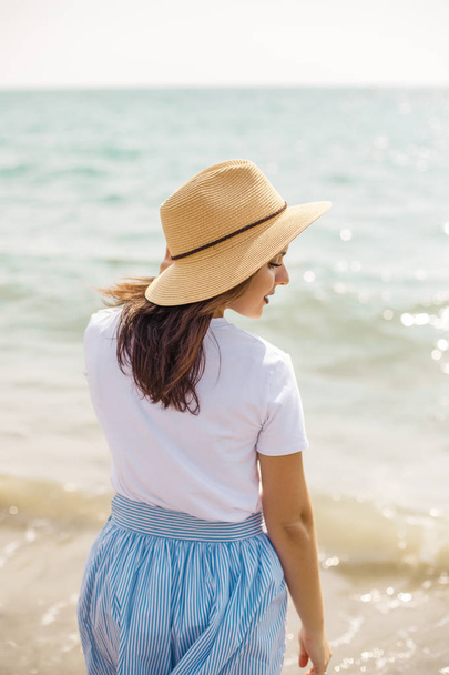 Young brunette girl in hat admiring the sea - Fotografie, Obrázek