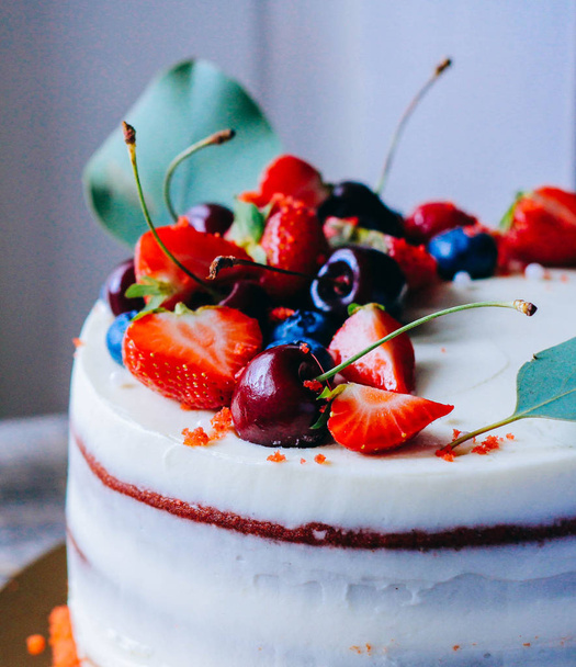 Κόκκινο βελούδινη τούρτα με διακόσμηση μούρο από φράουλα, μύρτιλο, κεράσι και ευκαλύπτου σε φόντο ξύλινη - Φωτογραφία, εικόνα