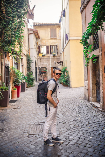 Young man with backpack walking on empty cobbled street - Φωτογραφία, εικόνα