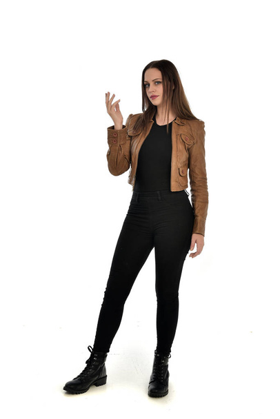 retrato de longitud completa de chica morena con chaqueta de cuero marrón. pose de pie sobre fondo blanco
. - Foto, Imagen