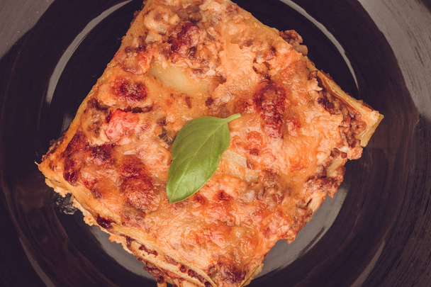 Tradiční italské lasagne s mletým hovězím, tomatová omáčka a zelené bazalky na tmavá deska - Fotografie, Obrázek