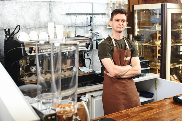 male waiter with crossed arms standing at workplace in coffee shop - Foto, immagini