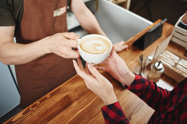 woman picking up cup with coffee from barista, close-up - Foto, imagen