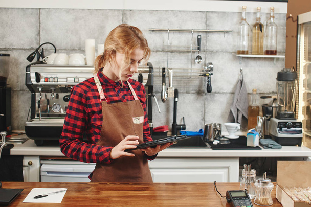 attractive barista using tablet pc at workplace in coffee shop  - Photo, image