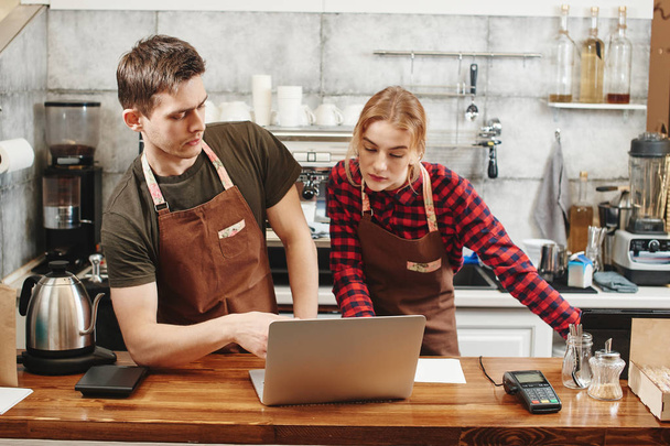 two baristas using laptop at workplace in coffee shop, learning concept  - Photo, Image