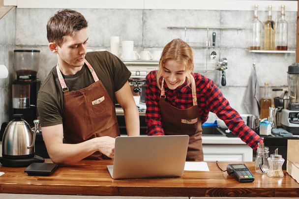 two baristas using laptop at workplace in coffee shop, learning concept  - Photo, image