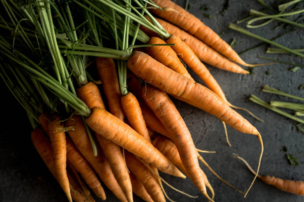 Biologische Nantes wortelen op rustieke donkere achtergrond. Verse Superfood gezond eten Concept. - Foto, afbeelding