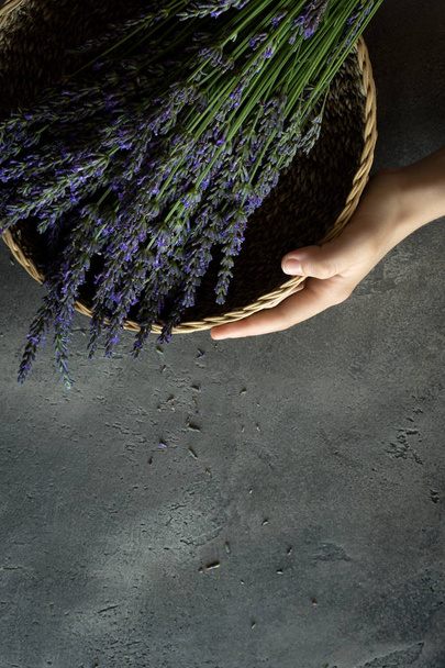 Vrouwelijke handen met lavendel boeket bloemen op rustieke donkere achtergrond - Foto, afbeelding