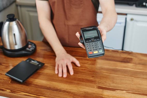 cashier holding card payment terminal over wooden surface of bar  - Foto, immagini