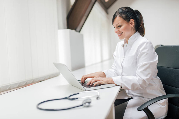 Female doctor typing report with laptop. - Foto, imagen