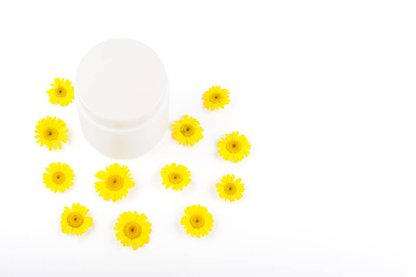 White mocap for cream, balm, mask and small yellow daisies on a white background. Isolate, close-up, view from above, fletley, copyspace - Photo, Image