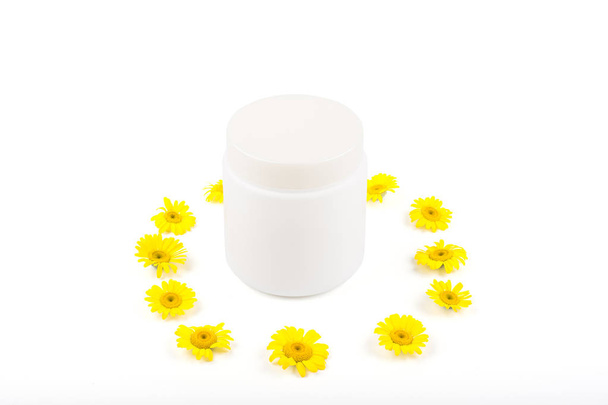 White mocap for cream, balm, mask and small yellow daisies on a white background. Isolate, close-up, front view - Fotoğraf, Görsel