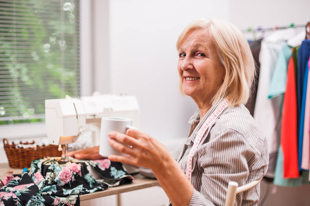 Adult woman is sewing in her studio. - Zdjęcie, obraz