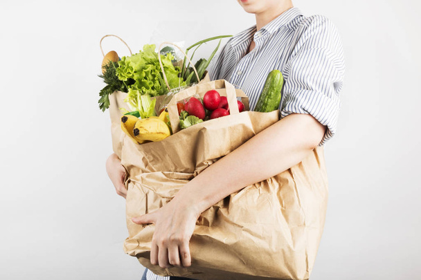 Young woman holding papers shopping bags on gray background - Foto, afbeelding
