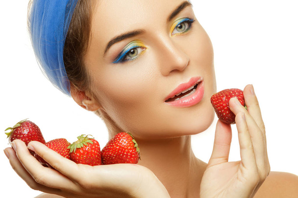 Mulher bonita com maquiagem colorida e morangos no fundo branco
 - Foto, Imagem