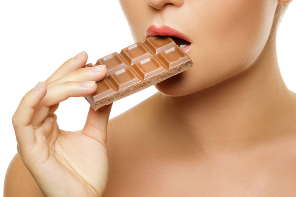 cropped image of young woman eating chocolate bar on white background - Fotografie, Obrázek