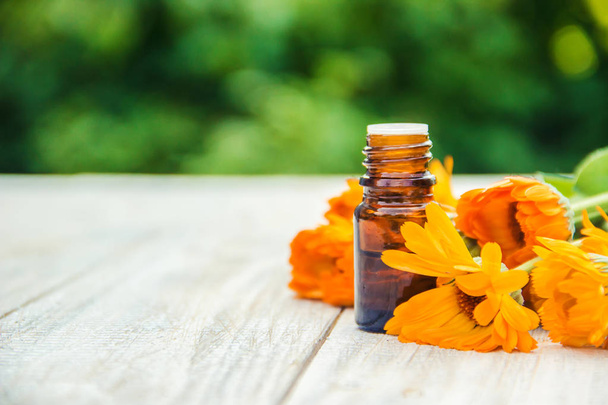 calendula extract and flowers in a small bottle. Selective focus.  - Фото, изображение