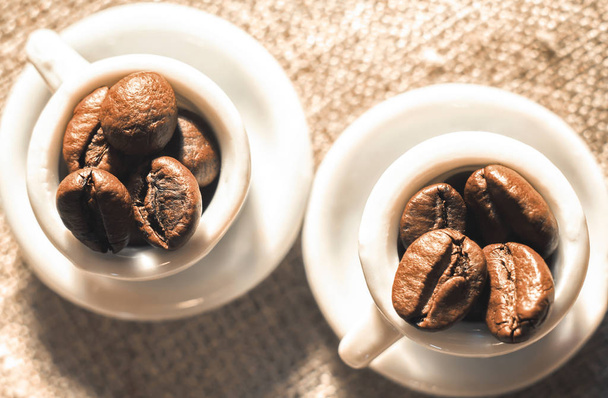 Koffiebonen in een kleine mooie porseleinen kopjes close-up. Sterke koffie poster. - Foto, afbeelding