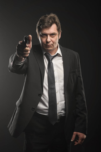 Handsome middle aged detective man with gun on dark background - Fotó, kép