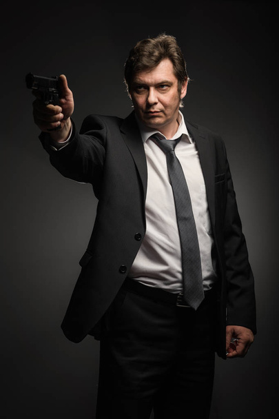Handsome middle aged detective man with gun on dark background - Fotografie, Obrázek