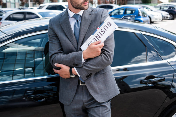Μερική άποψη του επιχειρηματία με εφημερίδα στέκεται στο αυτοκίνητο στον δρόμο - Φωτογραφία, εικόνα