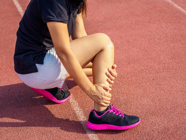 Mujer atleta tiene lesión en el tobillo, esguince de pierna durante el entrenamiento de carrera. concepto deportivo
. - Foto, Imagen