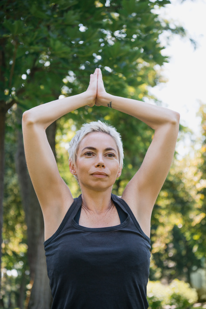 mujer practicando yoga con las manos en gesto namaste en parque
 - Foto, imagen