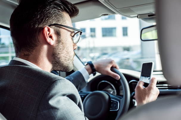 hombre de negocios usando el teléfono inteligente mientras conduce el coche
 - Foto, Imagen