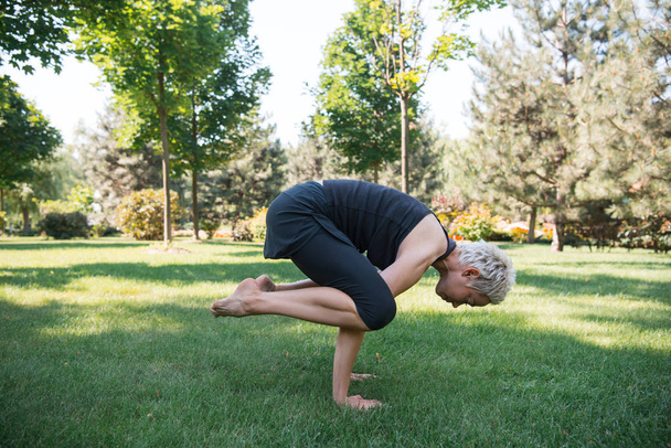 vista laterale della donna che pratica yoga e fare il posizionamento sulle mani nel parco
 - Foto, immagini