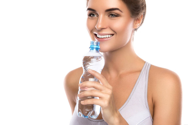 Ευτυχισμένη χαμογελαστή γυναίκα με ένα μπουκάλι του νερού πάνω από το λευκό φόντο - Φωτογραφία, εικόνα