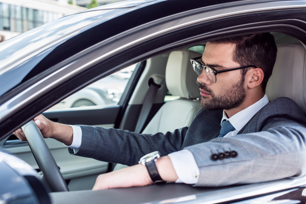 side view of businessman in eyeglasses driving car - Foto, afbeelding