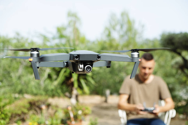 closeup ενός Καυκάσιος ανθρώπου λειτουργούν ένα drone, ελέγχεται εξ αποστάσεως με ένα smartphone, μέσα σε ένα φυσικό τοπίο - Φωτογραφία, εικόνα