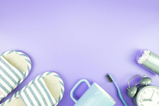 domácí zařízení hodiny ploché rozložení složení zubní kartáček brýle, ručník a přezůvky pohled shora na modré a fialové fialový konceptu - Fotografie, Obrázek
