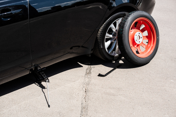 close up vista de Jack parafuso, roda chave e pneu perto de carro quebrado na rua
 - Foto, Imagem