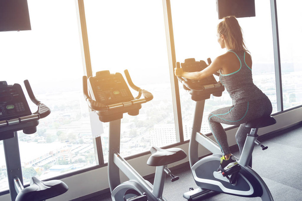 sporty young woman on stationary bike in the gym - Photo, Image