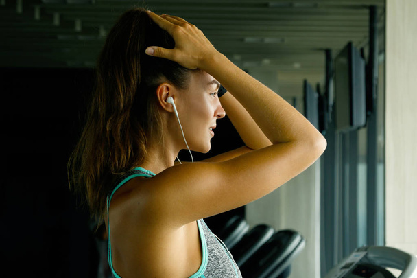 Sporty woman listening music during workout in gym - Zdjęcie, obraz