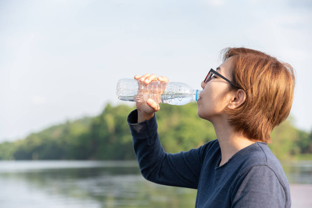 Asian Woman traveler drinking water on natural background. - Фото, изображение