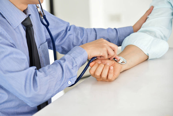 Cierra las manos. El médico asiático está midiendo la presión arterial de un paciente. Estetoscopio. Salud. Pulso
. - Foto, Imagen