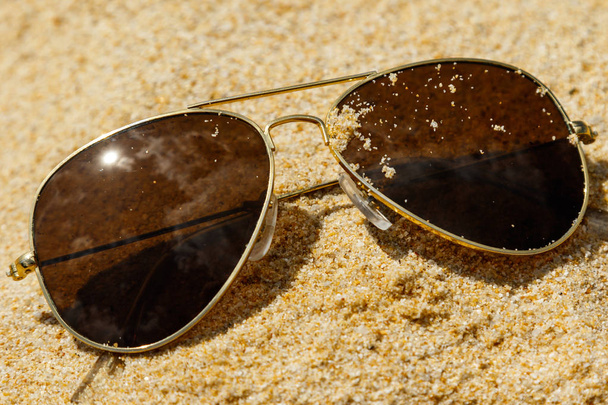 Close up view of Sunglasses lying on sand - Foto, imagen