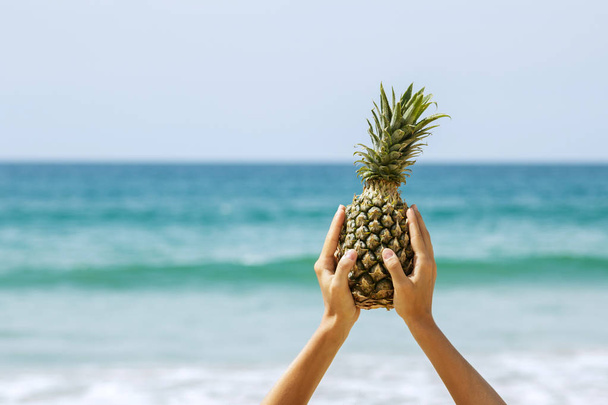 Ripe pineapple in female hands on beach - Zdjęcie, obraz