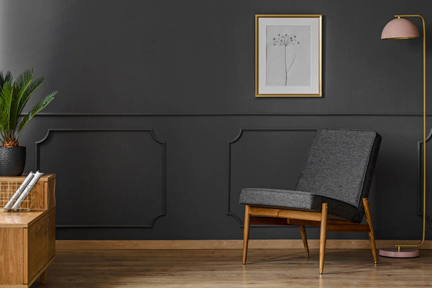 Black chair in a dark, spacious retro living room interior with lamp, cabinet, wooden floor and black walls - Fotoğraf, Görsel