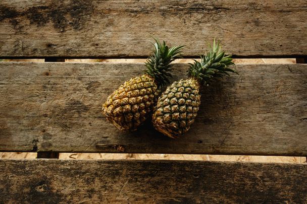 Two pineapples on wooden surface, top view - Фото, зображення