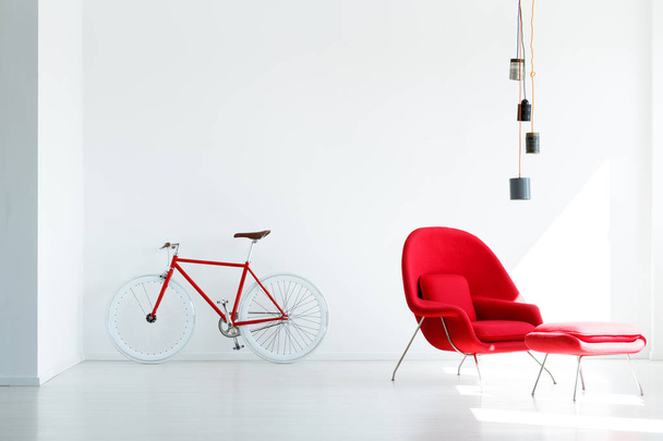 Red bicycle and armchair under lamp in white minimal apartment interior. Real photo - Valokuva, kuva