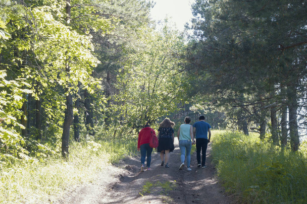 Group of young people walking on the forest path at sunny day - Photo, Image
