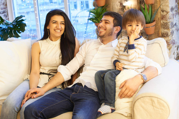 Aziatische en gelukkige familie zitten samen op witte sofa in appartement  - Foto, afbeelding